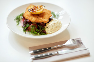 close up of fish salad with roasted lemon on plate