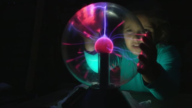 Girl touching her hands and sees a plasma ball. Night Light lamp Tesla 