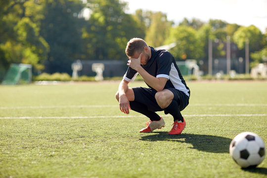 sad soccer player with ball on football field