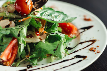 Salad with greens and mushrooms on a white plate