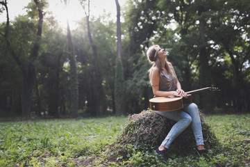 Beautiful woman playing guitar in nature