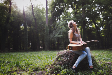 Beautiful woman playing guitar in nature