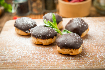 Tasty eclairs on wooden table