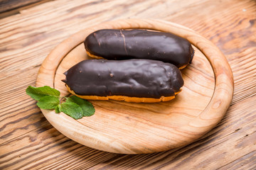 Tasty eclairs on wooden table