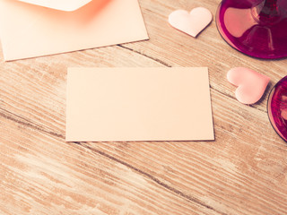 Fototapeta premium Blank pink paper letter note with hearts to fill with your text on wooden textured background. Valentine's day wedding romantic date invitation. Toned