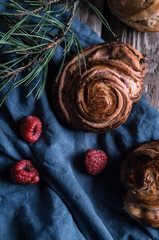 Buns with white chocolate and raspberries on a wooden table with pieces of chocolate, berries and pine branches