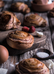 Buns with white chocolate and raspberries on a wooden table with pieces of chocolate, berries and pine branches