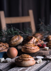 Buns with white chocolate and raspberries on a wooden table with pieces of chocolate, berries and pine branches