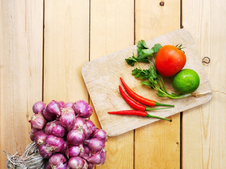 Various kinds of fresh vegetables for cooking on a wooden chopping board on a wooden floor.
