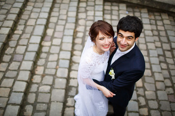 Fototapeta na wymiar smiling bride & groom standing on stone stairs