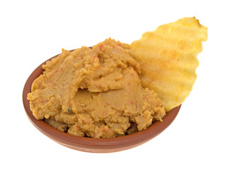 Hummus dip with a potato chip in a bowl side view isolated on a white background.