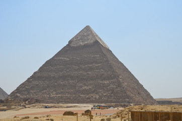 Fototapeta na wymiar Pyramid in sand dust under gray clouds