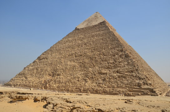 Pyramid in sand dust under gray clouds