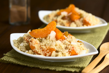 Couscous dessert with apricots, yellow raisins, coconut flakes and cinnamon, photographed with natural light (Selective Focus, Focus on the apricot on the first dessert)