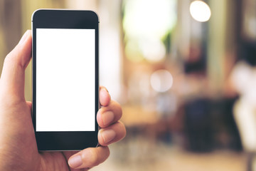 Mockup image of hand holding black mobile phone with blank white screen in cafe