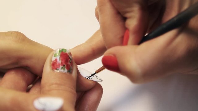 Cosmetic shop manicure session, woman hand drawing heart pattern on white nail polish, close up