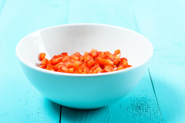 Chopped Red Capsicum In White Bowl On Turquoise Table
