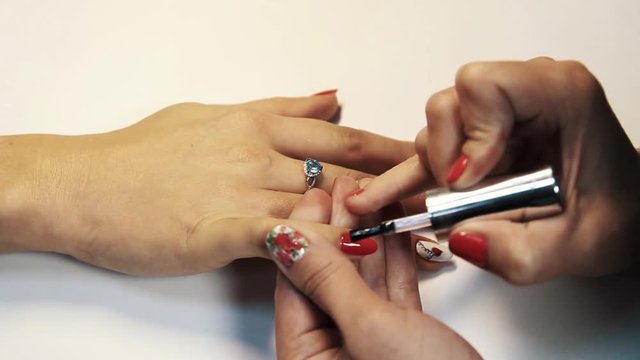 Finishing manicure finger nail polish session, applying transparent varnish, white table close up