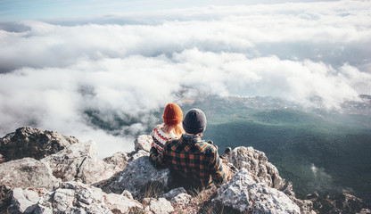 Couple Man and Woman sitting on cliff enjoying mountains and clouds landscape Love and Travel happy...