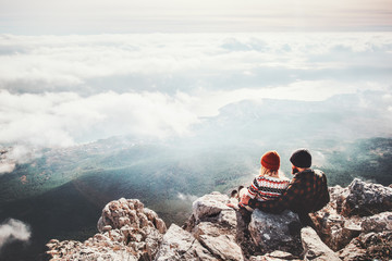 Couple travelers Man and Woman sitting on cliff relaxing mountains and clouds aerial view  Love and...