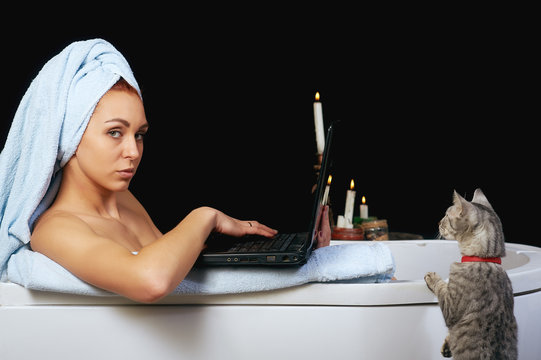 A woman working at a laptop while taking a bath