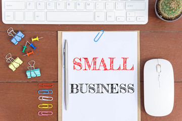 Text Small business on white paper which has keyboard mouse pen and office equipment on wood background / business concept.