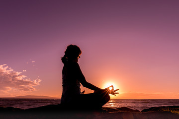 Woman Silhouetted Practicing Yoga on the Beach at Sunset