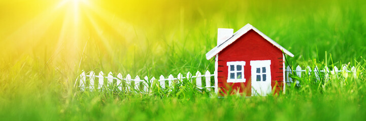 red wooden house model on the grass in garden