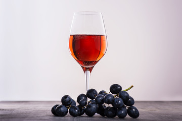 Glass of red wine with bunch of red grapes on wooden table