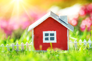red wooden house model on the grass in garden