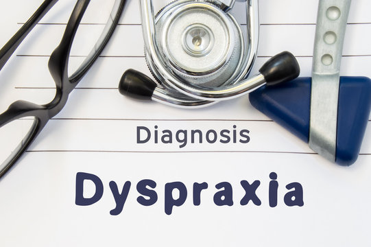 Neurological diagnosis of Dyspraxia. Neurological hammer, stethoscope and doctor's glasses lie on doctor workplace on sheet of notebook, labeled with the title of medical diagnosis of Dyspraxia