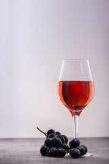 Glass of red wine with ripe grapes on wooden table