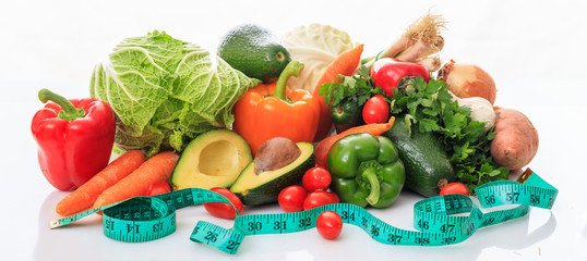 Variety of vegetables and measure tape on white background