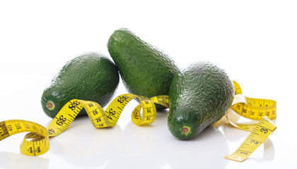 Avocados and measure tape on white background