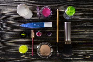 Set of decorative cosmetics and nail polish, face cream on dark wooden background, top view.