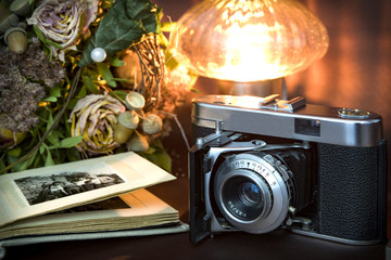 Alter Fotoapparat mit Fotoalbum, Blumen und Kerzenlicht