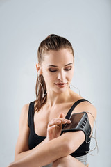 Obraz premium Joyful woman in sportswear using smartphone