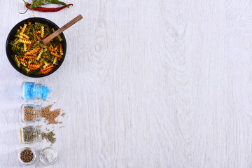 Obraz na płótnie Canvas plate with pasta, spoon, spices in jars, chili pepper