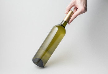 Hand is holding wine bottle on gray background