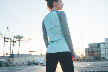 Athletic woman standing in industrial area. Relaxing after nice workout. Sporty and fit body