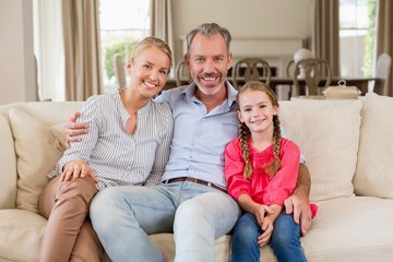 Obraz premium Portrait of smiling parents and daughter sitting 