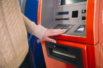 Young woman withdrawing money from credit card at ATM. Selective focus.