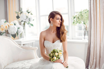 Obraz na płótnie Canvas Bride in beautiful dress sitting resting on sofa indoors