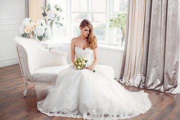 Fototapeta na wymiar Bride in beautiful dress sitting resting on sofa indoors