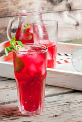 Summer iced drink - tea or juice with ice and mint. On rustic wooden table, with white tray, copy space