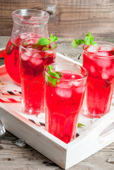 Summer iced drink - tea or juice with ice and mint. On rustic wooden table, with white tray, copy space