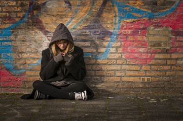runaway girl sits in front of a wall with graffiti - Powered by Adobe