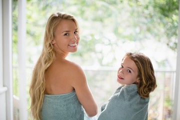 Smiling mother and daughter in towel at bathroom