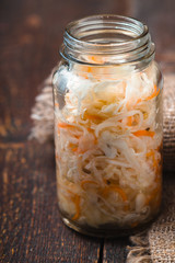 Sauerkraut in a glass jar on wooden boards