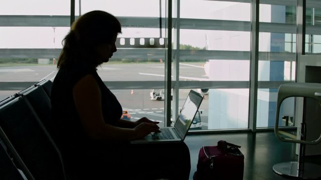 Woman working on a laptop while waiting for the plane at the airport